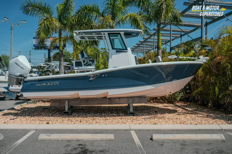 The Image of 2026 Blackfin 242 HB boat displayed outdoors at a dealership with palm trees. - 1