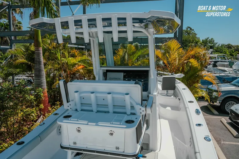 Slide: The Image of 2026 Blackfin 242 HB boat with T-top and fishing rod holders, surrounded by tropical plants. - 8