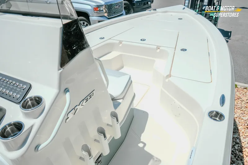 Slide: The Image of 2026 Skeeter SX221 boat interior with console, cup holders, and seating in a showroom setting. - 16