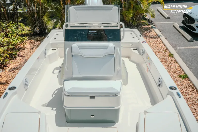 Slide: The Image of 2026 Skeeter SX221 boat interior with seating, console, and storage, parked outdoors. - 23