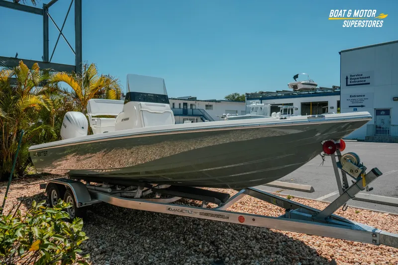 Slide: The Image of 2026 Skeeter SX221 boat on trailer at dealership, sunny day, palm trees nearby. - 4