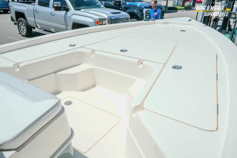Slide: The Image of 2026 Skeeter SX221 boat deck with storage compartments, parked near trucks. - 6