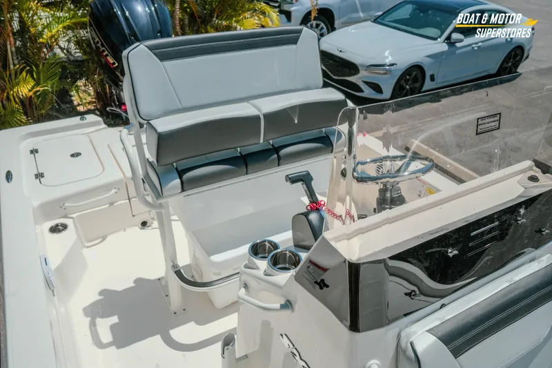 Slide: The Image of 2026 Skeeter SX221 boat interior with seating and steering console, parked near cars. - 22
