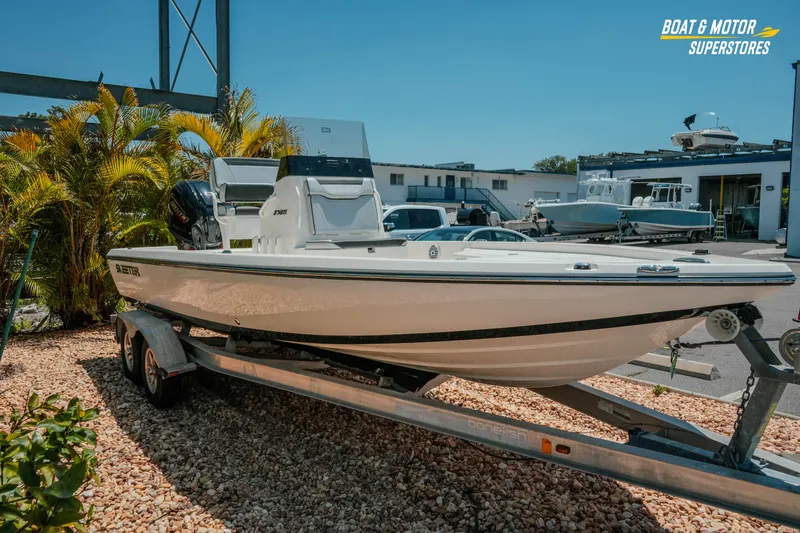 Slide: The Image of 2026 Skeeter SX221 boat on trailer at dealership, surrounded by palm trees and other boats. - 4