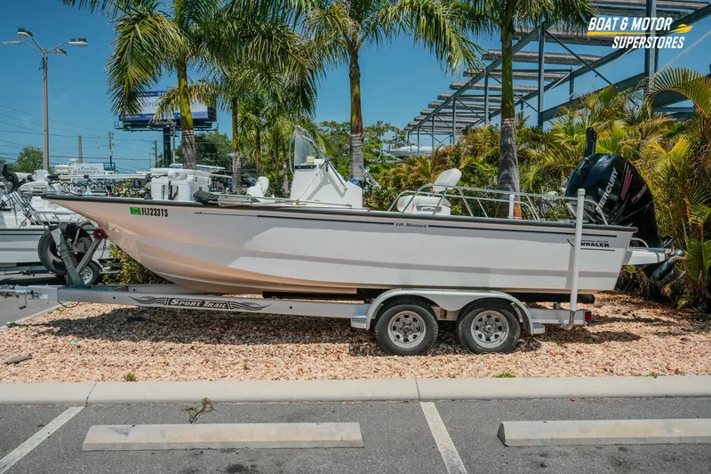 The Image of 2016 Boston Whaler 210 Montauk boat on trailer, parked near palm trees. - 1