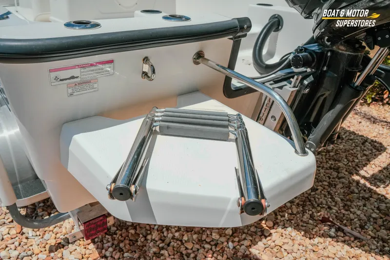Slide: The Image of 2016 Boston Whaler 210 Montauk boat ladder and motor detail on gravel surface. - 10