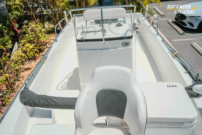 Slide: The Image of 2016 Boston Whaler 210 Montauk boat interior with seating and console, parked outdoors. - 21