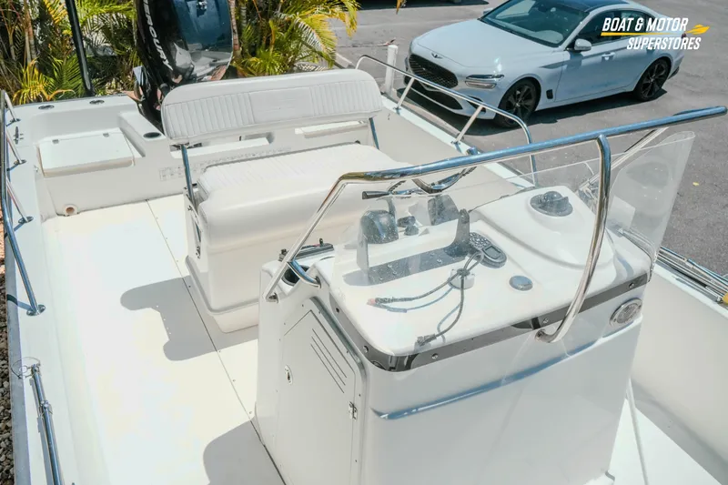 Slide: The Image of 2016 Boston Whaler 210 Montauk boat interior with console and seating, parked outdoors. - 22