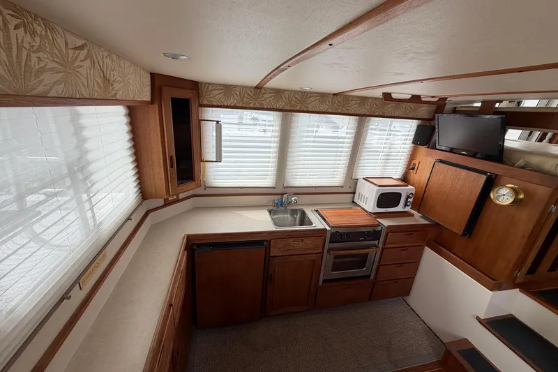 Slide: The Image of Interior of 2007 Nordic Tug 32, featuring a compact kitchen with wooden cabinetry. - 13