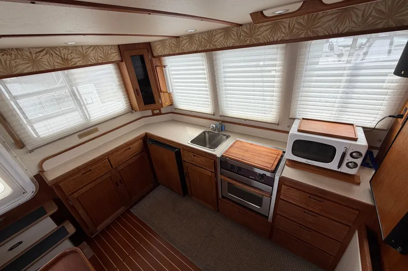 Slide: The Image of 2007 Nordic Tug 32 interior kitchen with wooden cabinets, sink, stove, and microwave. - 14