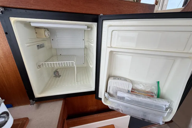 Slide: The Image of Open refrigerator inside a 2007 Nordic Tug 32 boat, showing interior shelves and door storage. - 16