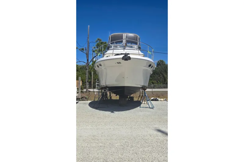 Slide: The Image of 2001 Sea Ray 400 Sedan Bridge yacht, side view, docked on gravel. - 29