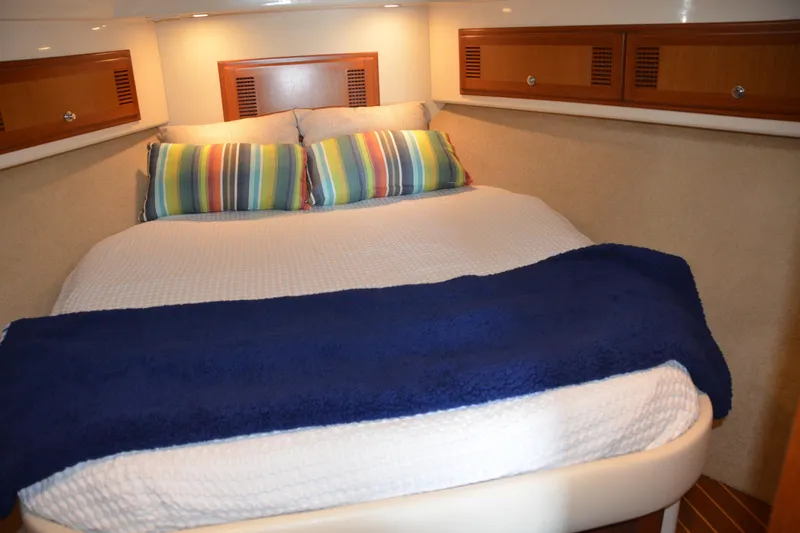 Slide: The Image of Cozy cabin interior of 2001 Cabo 35 Flybridge with striped pillows and blue blanket. - 29