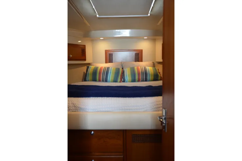 Slide: The Image of Cozy cabin interior of 2001 Cabo 35 Flybridge with colorful striped pillows. - 32