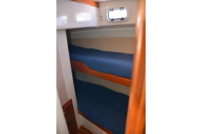 Slide: The Image of Bunk beds in 2001 Cabo 35 Flybridge cabin with blue bedding and wooden accents. - 38