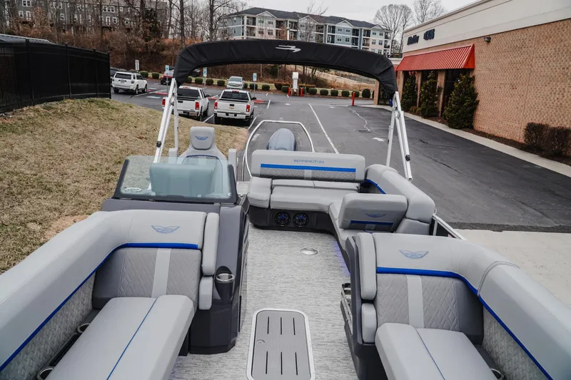 Slide: The Image of 2025 Bennington 24MSB pontoon boat with luxurious seating and modern design in a parking area. - 13