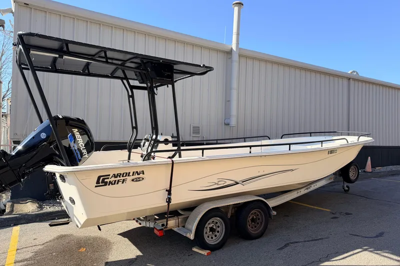 Slide: The Image of 2017 Carolina Skiff 258 DLV boat on trailer, parked near a building. - 2