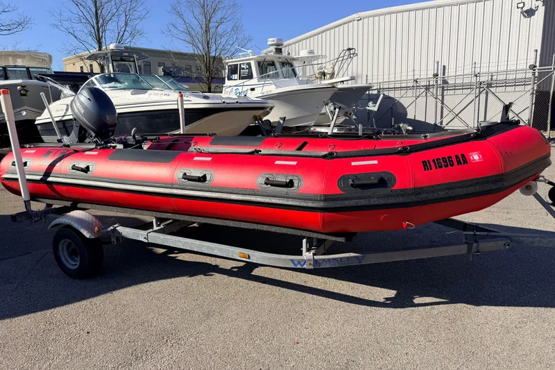 The Image of Red 2025 Inmar 530RHD inflatable boat on trailer, parked outdoors near other boats. - 0