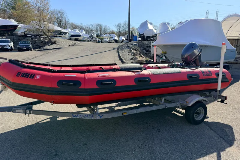 Slide: The Image of Red 2025 Inmar 530RHD inflatable boat on trailer, parked outdoors. - 2