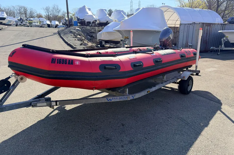 Slide: The Image of Red 2025 Inmar 530RHD inflatable boat on trailer, parked outdoors in a boatyard. - 3