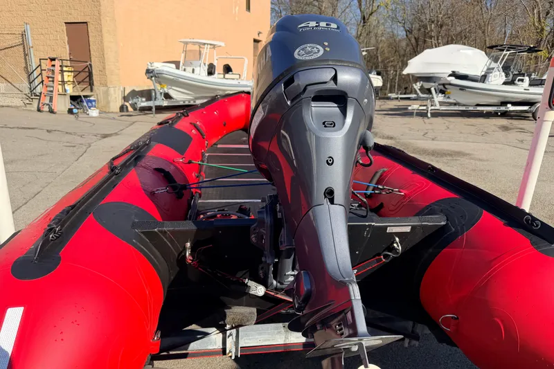 Slide: The Image of Red 2025 Inmar 530RHD inflatable boat with outboard motor in a parking lot. - 6