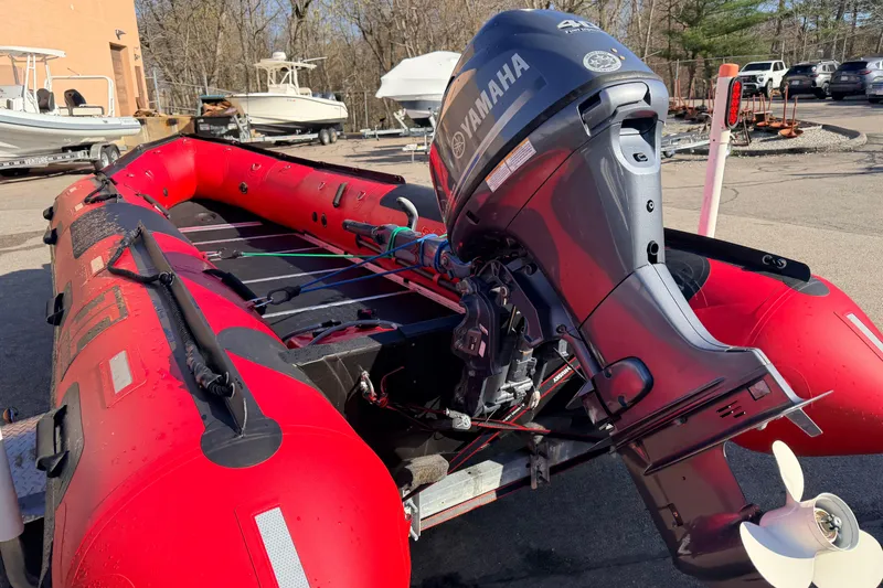 Slide: The Image of Red 2025 Inmar 530RHD inflatable boat with Yamaha outboard motor in a marina setting. - 7