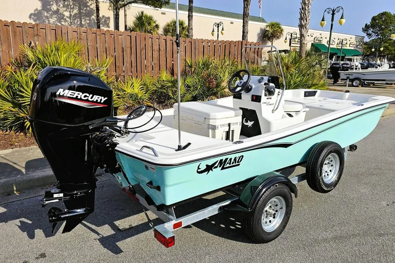 Slide: The Image of 2026 Mako Pro Skiff 15 CC boat with Mercury engine on trailer, parked outdoors. - 2