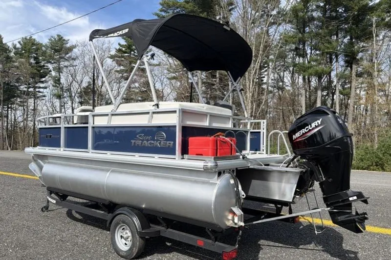 Slide: The Image of 2026 Sun Tracker Bass Buggy 16 XL Select pontoon boat with Mercury outboard motor on trailer. - 2