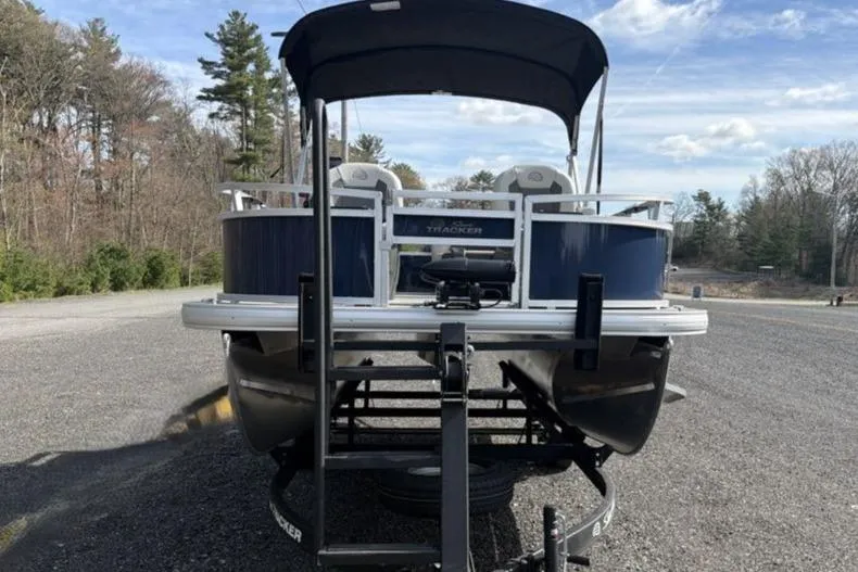 Slide: The Image of 2026 Sun Tracker Bass Buggy 16 XL Select pontoon boat on trailer, parked outdoors. - 6