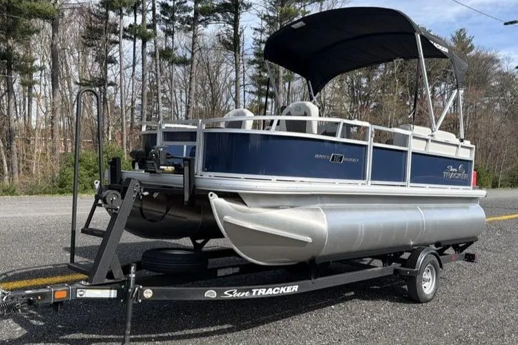 The Image of 2026 Sun Tracker Bass Buggy 16 XL Select pontoon boat on trailer, parked on roadside. - 0