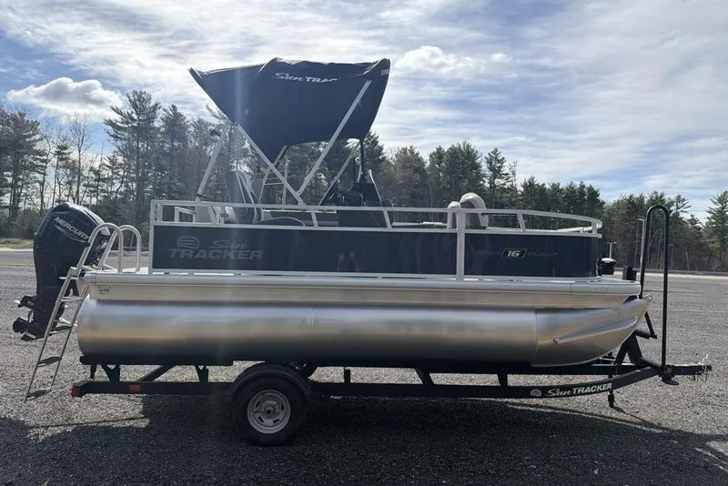 Slide: The Image of 2026 Sun Tracker Bass Buggy 16 XL Select pontoon boat on trailer, outdoors. - 4