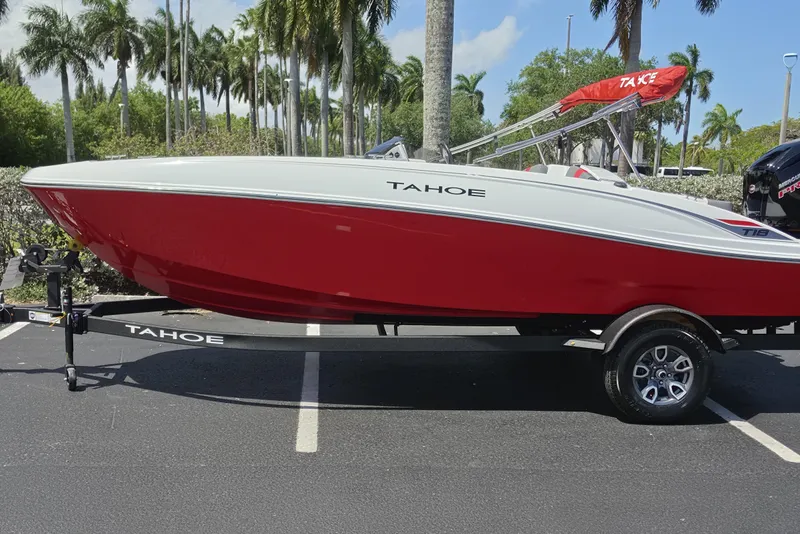 The Image of 2026 Tahoe T18 boat with red and white design on a trailer, parked outdoors. - 0