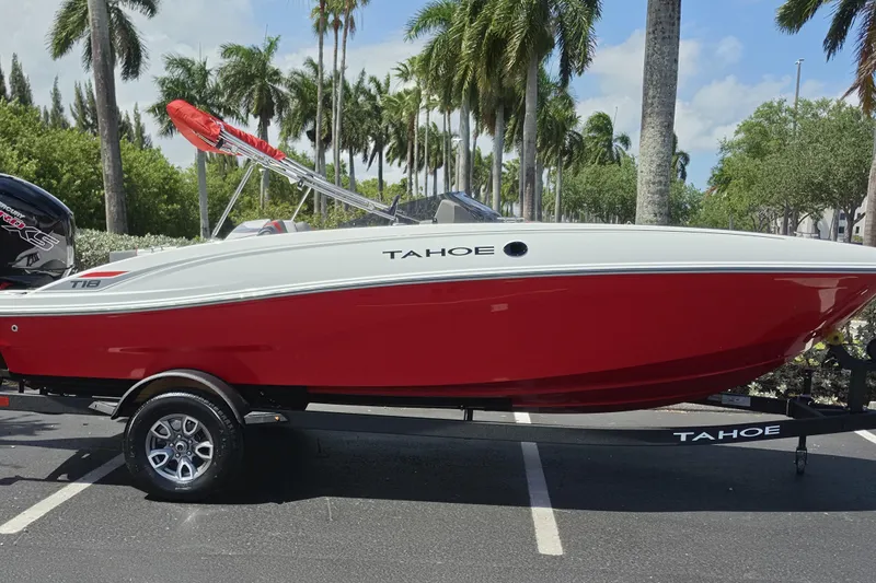 Slide: The Image of 2026 Tahoe T18 boat in vibrant red, parked with palm trees in the background. - 1
