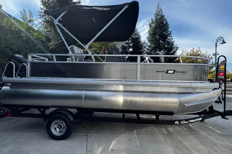 The Image of 2026 Sun Tracker Bass Buggy 18 DLX pontoon boat on trailer, parked outdoors. - 0