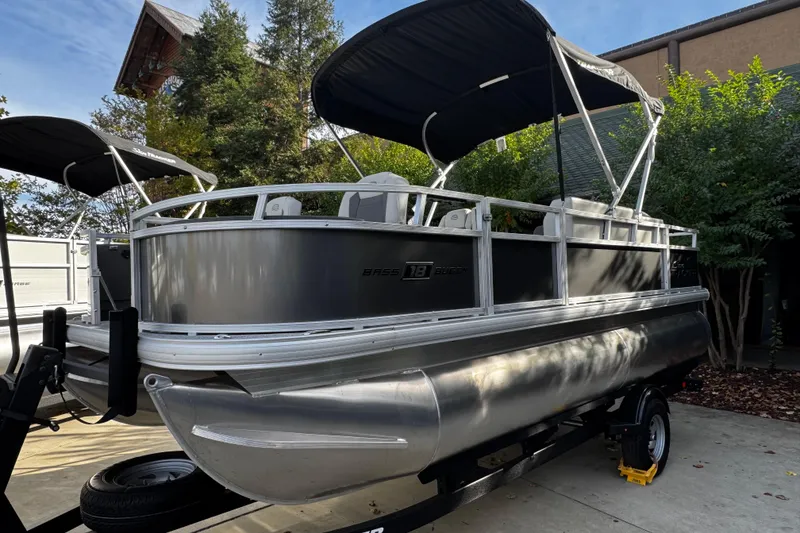 Slide: The Image of 2026 Sun Tracker Bass Buggy 18 DLX pontoon boat with canopy, parked on trailer. - 2