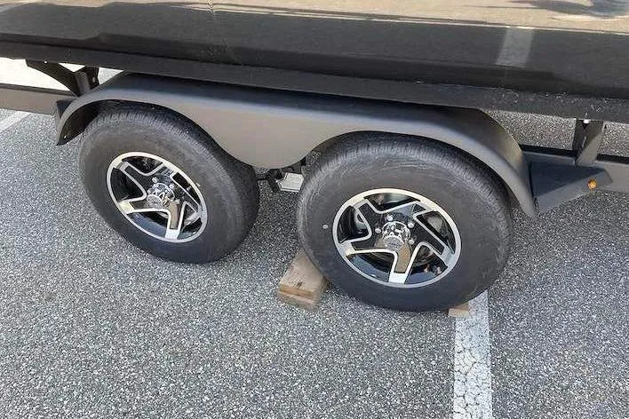Slide: The Image of A Ranger 223FC boat trailer with two sturdy wheels on a parking lot. - 15
