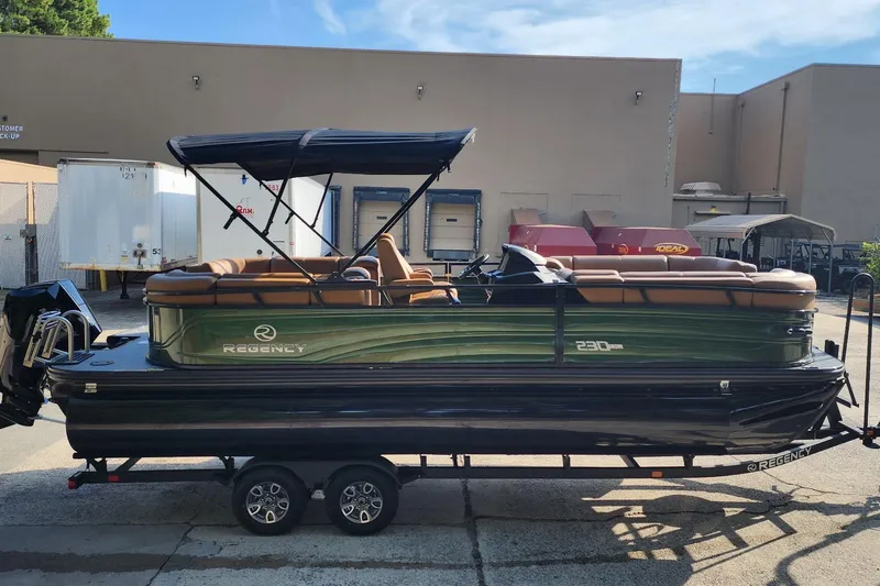 Slide: The Image of 2026 Regency 230 DL pontoon boat on trailer, featuring sleek design and canopy. - 1