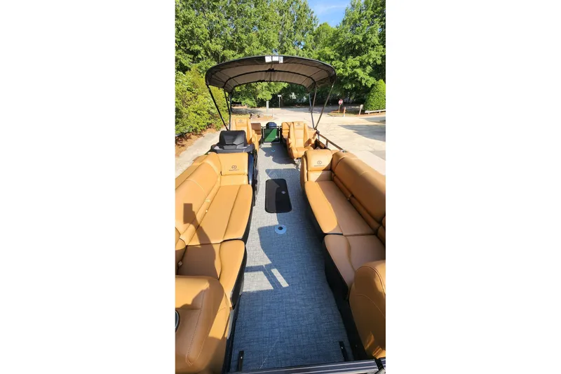 Slide: The Image of 2026 Regency 230 DL pontoon boat with tan seating and canopy, parked outdoors. - 4