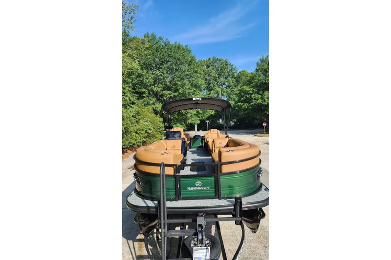 Slide: The Image of 2026 Regency 230 DL pontoon boat on trailer, surrounded by lush greenery. - 2