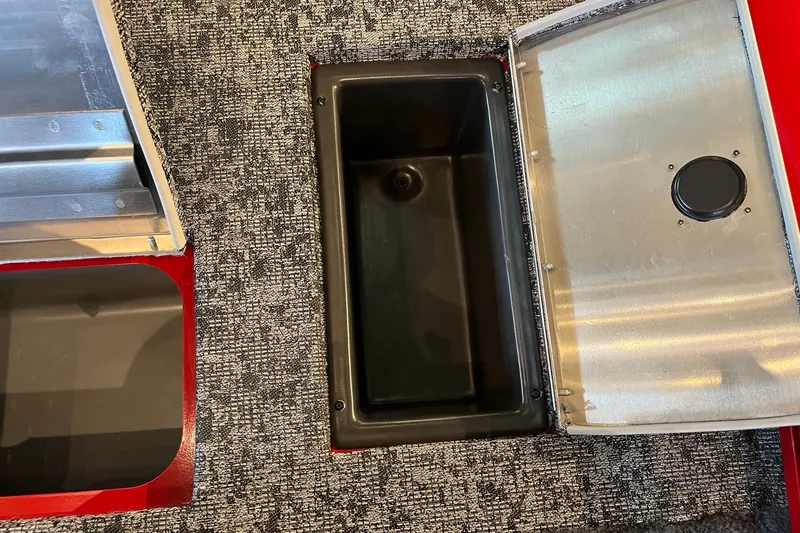 Slide: The Image of Open storage compartment in 2026 Tracker Pro Team 175 boat, featuring a black interior and metallic lid. - 18