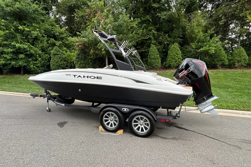 Slide: The Image of 2026 Tahoe 1950 boat on trailer, parked on road with lush greenery background. - 4