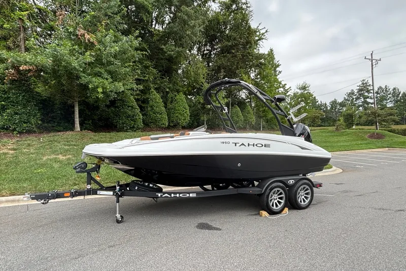 Slide: The Image of 2026 Tahoe 1950 boat on trailer in parking lot, surrounded by greenery. - 1