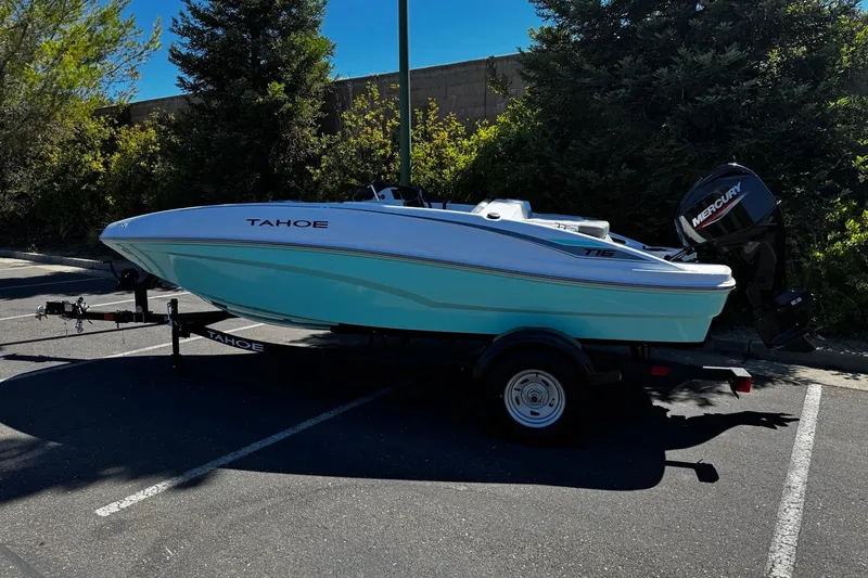 Slide: The Image of 2026 Tahoe T16 boat on trailer in parking lot, surrounded by trees. - 1