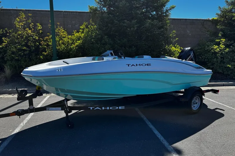 Slide: The Image of 2026 Tahoe T16 boat on trailer in parking lot, surrounded by greenery. - 2