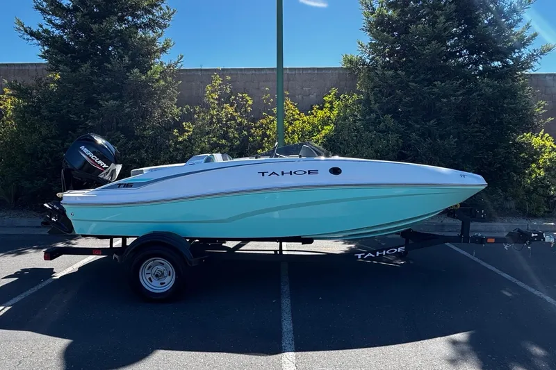 The Image of 2026 Tahoe T16 boat on trailer, parked outdoors, with trees in the background. - 0