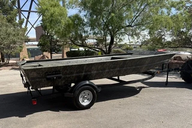 Slide: The Image of 2026 Tracker Grizzly 1754 Utility boat on trailer, parked outdoors under trees. - 2