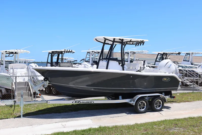 Slide: The Image of 2026 Sea Hunt Ultra 219 boat on trailer, parked in marina under clear blue sky. - 16