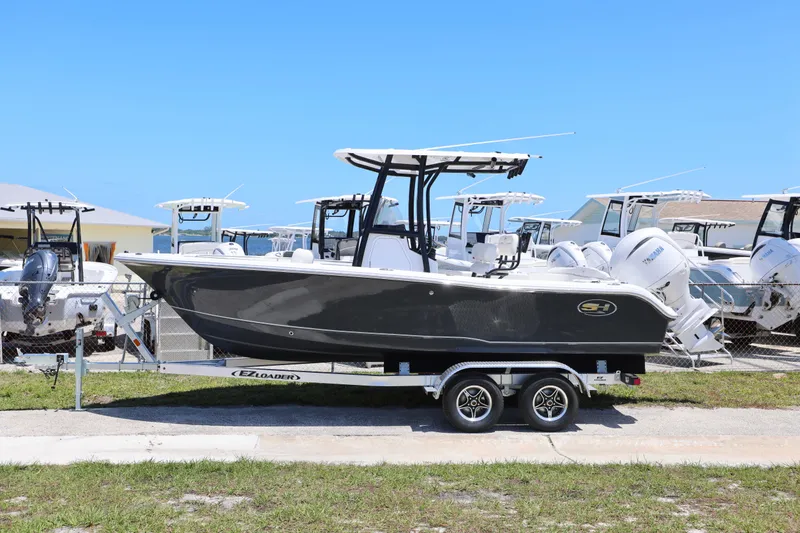 Slide: The Image of 2026 Sea Hunt Ultra 219 boat on trailer, displayed outdoors under clear blue sky. - 17