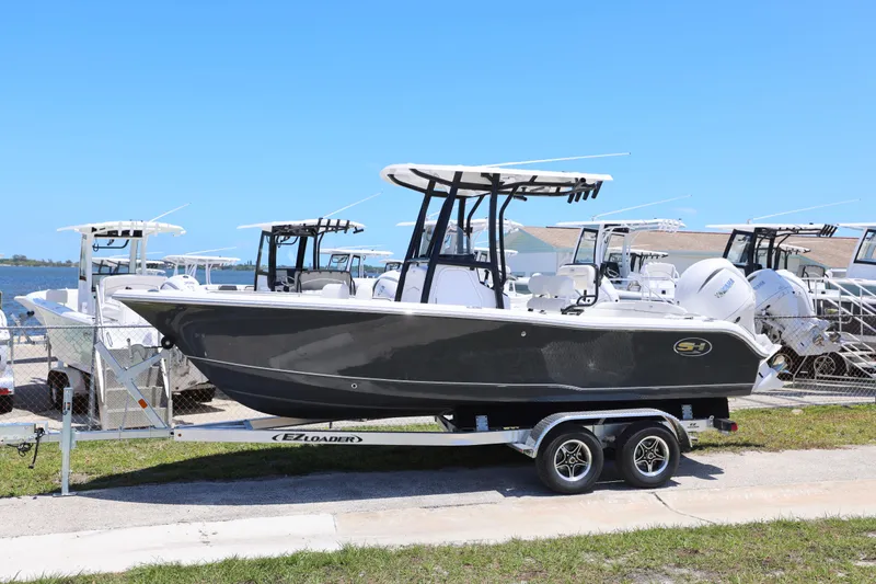 Slide: The Image of 2026 Sea Hunt Ultra 219 boat on trailer, parked outdoors under clear blue sky. - 18