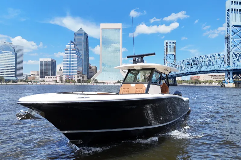 Slide: The Image of 2021 Scout 330 LXF boat cruising near a blue bridge under a clear sky. - 7